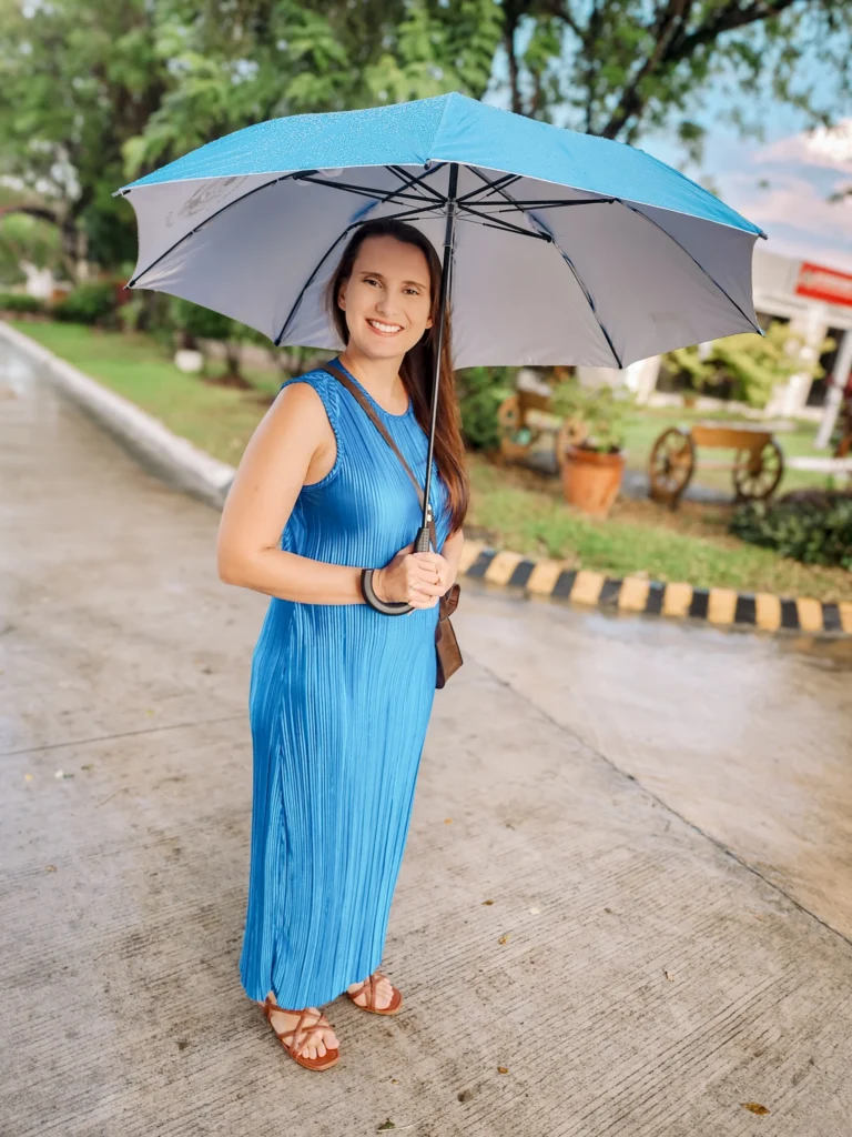 Smiling woman holding an umbrella on a rainy day in the Philippines, representing everyday expat life