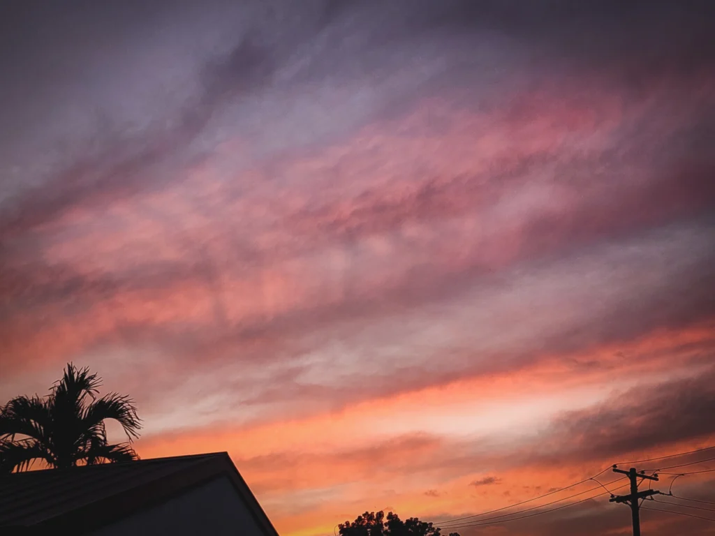 Colorful sunset sky over Clark Freeport in Pampanga, Philippines with palm trees and power lines in silhouette