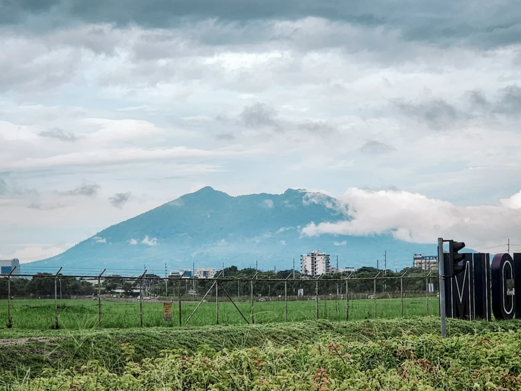 Mount Arayat seen from Clark Freeport in Pampanga, Philippines with clouds covering its peak and fields in the foreground