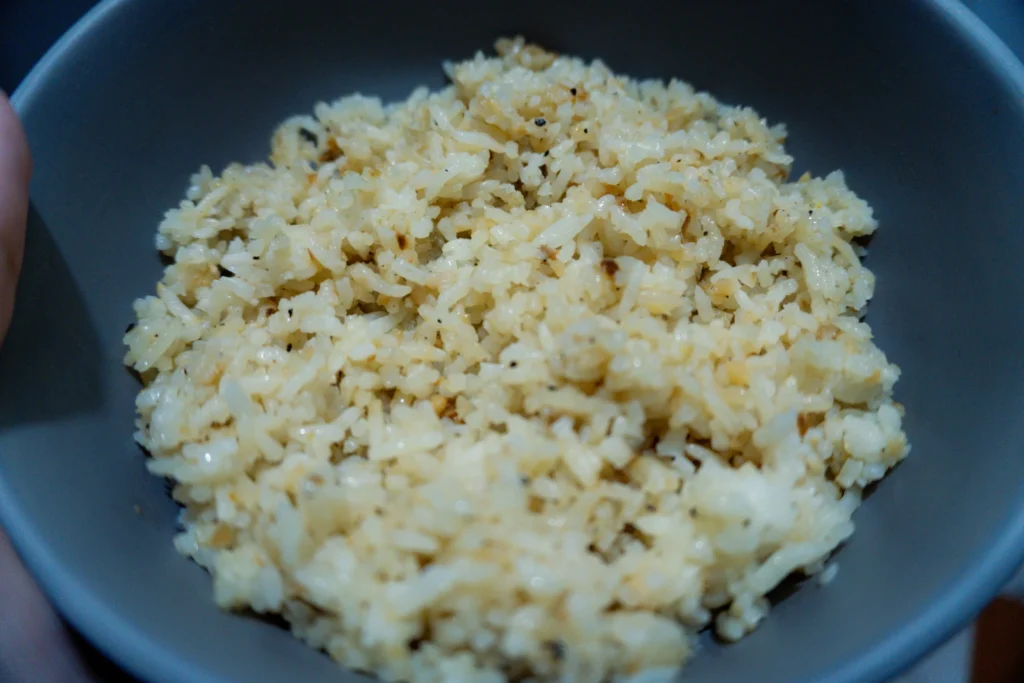 A close-up of a bowl of Filipino garlic fried rice, topped with golden-brown toasted garlic pieces.