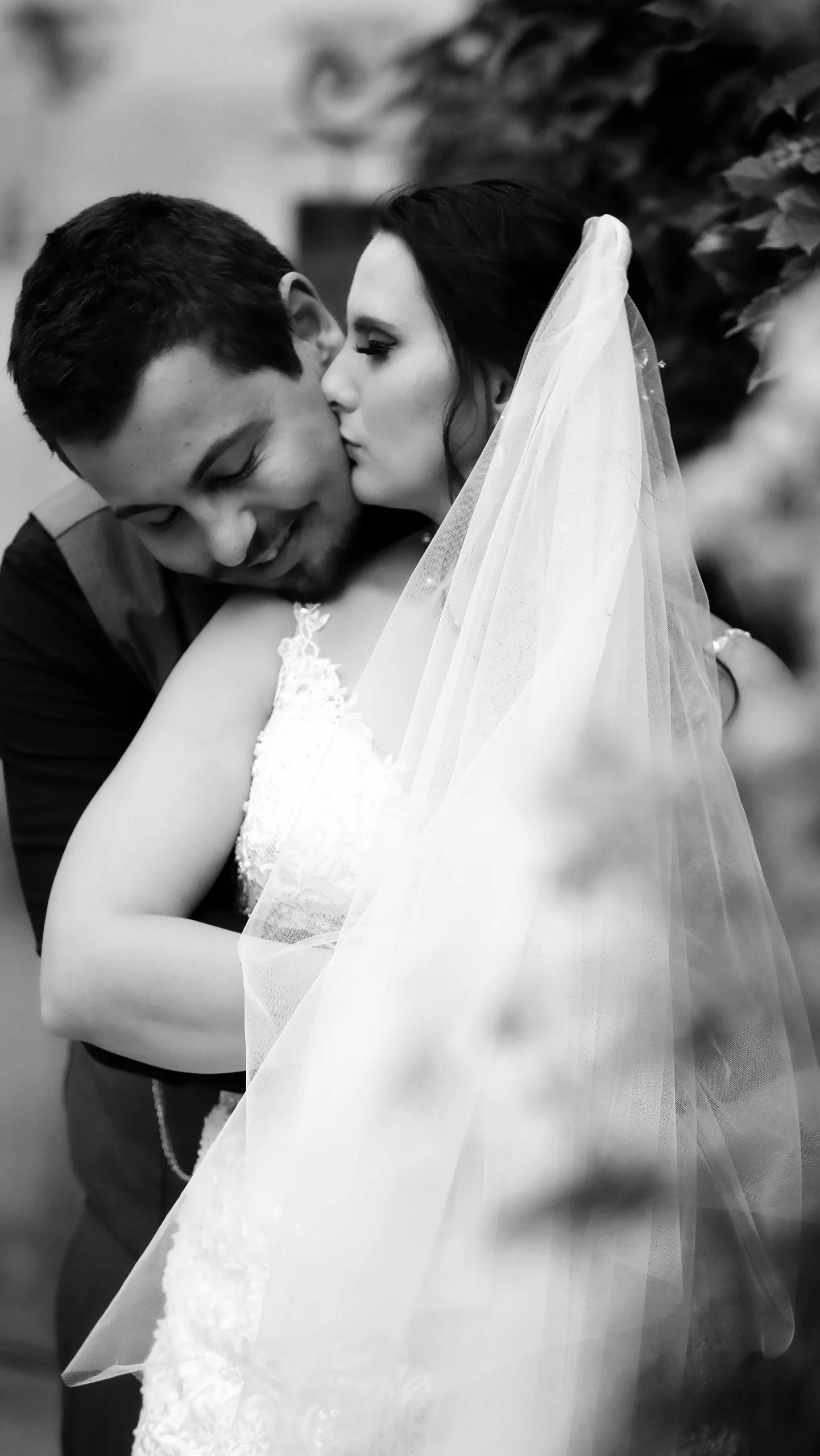 Black and white photo of a smiling bride and groom on their wedding day.