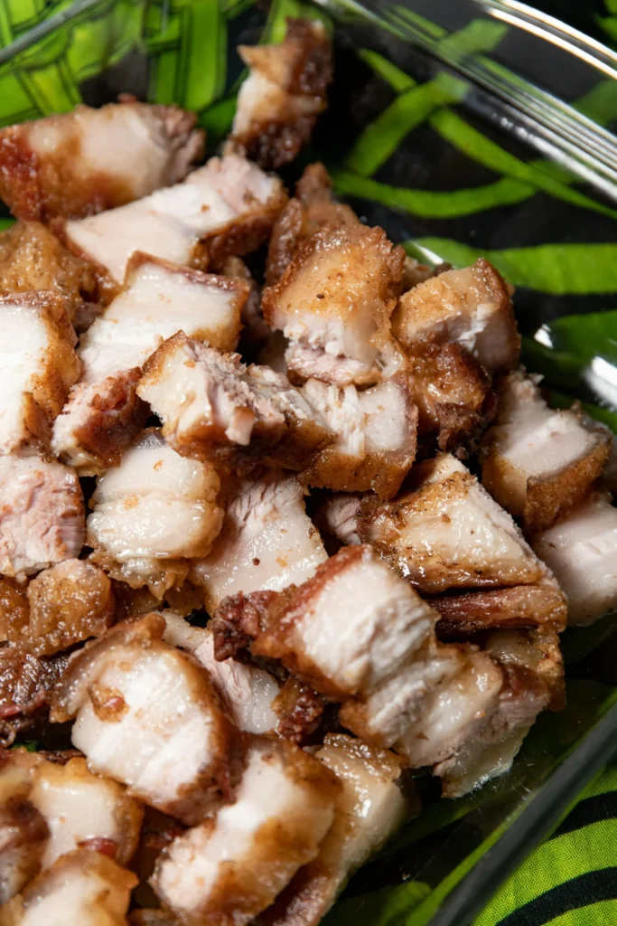 A serving of Filipino lechon pieces, highlighting the perfect, crackling-crisp skin and succulent meat.