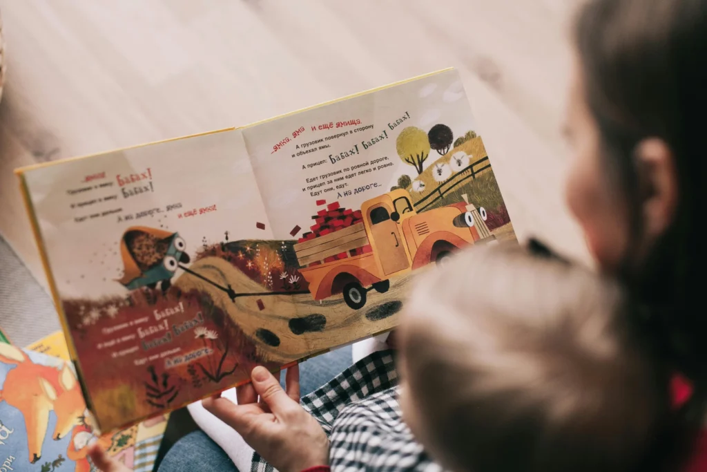 Mother reading a colorful children’s book to her young child during a quiet bonding moment. Motherhood and Guilt